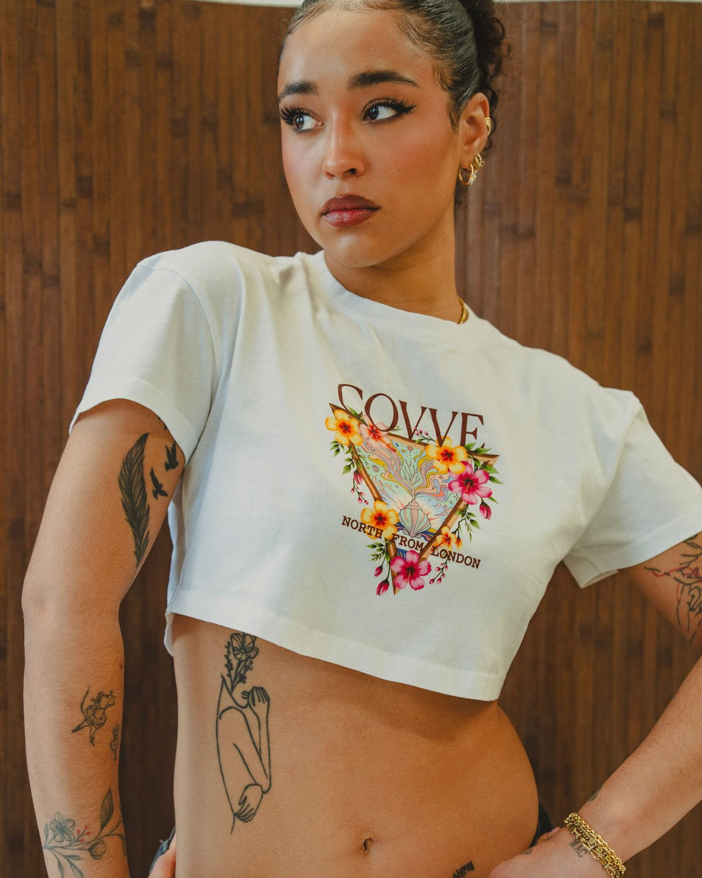 Model wearing the White City Bloom cropped T-shirt against a wooden wall